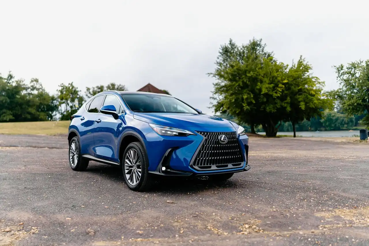 Coche Lexus azul estacionado al aire libre, sobre pavimento, con árboles de fondo.