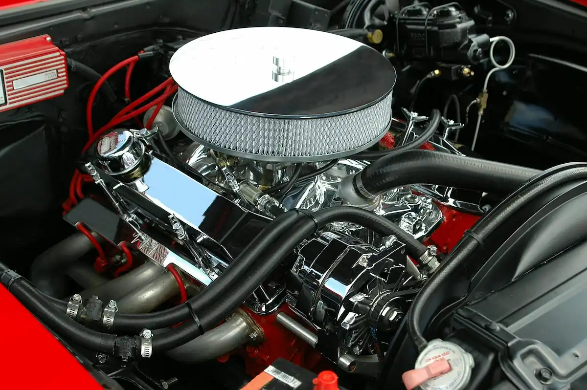 Motor de automóvil de alto rendimiento con componentes metálicos pulidos y cableado visible, preparado para revisión en taller.